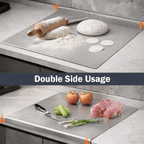 Double sided stainless steel chopping board used for rolling dough and cutting vegetables on a kitchen counter.