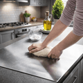 Person kneading dough on a stainless steel chopping board in a kitchen.